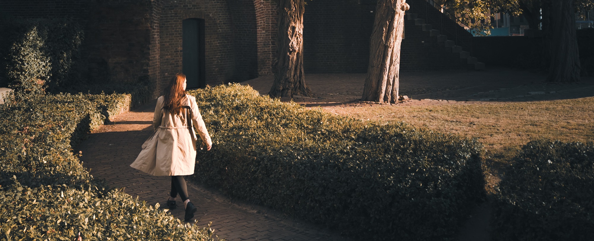 Vrouw wandelt ontspannen langs de Rattentoren in Roermond, omgeven door warme herfstkleuren.