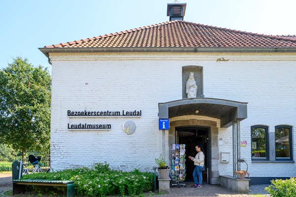 Vrouw kijkt naar de ansichtkaarten die buiten zijn gezet voor de ingang van het Bezoekerscentrum Leudal / Leudalmuseum.