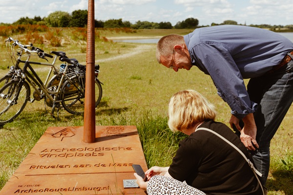 Woman and man stopped at an Archeo Route Limburg spear during their bike ride to use the app to see what happened at that site.