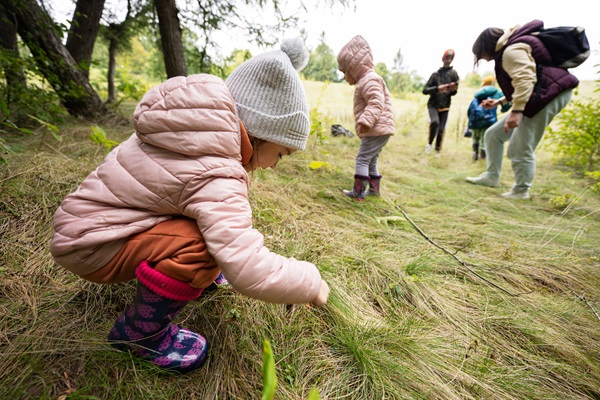 Kinder machen gemeinsam mit ihren Eltern und einem Guide einen geführten Spaziergang in der Natur.