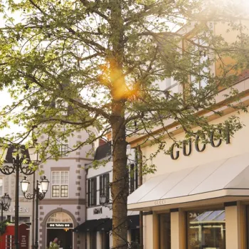 Winkelstraat bij Designer Outlet Roermond met modewinkels en groen in de straat.